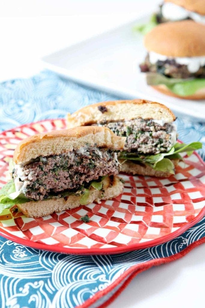 A burger sits on a colorful red plate, ready for eating