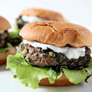 Three Spinach and Feta Burgers sit on a white platter, ready for consuming