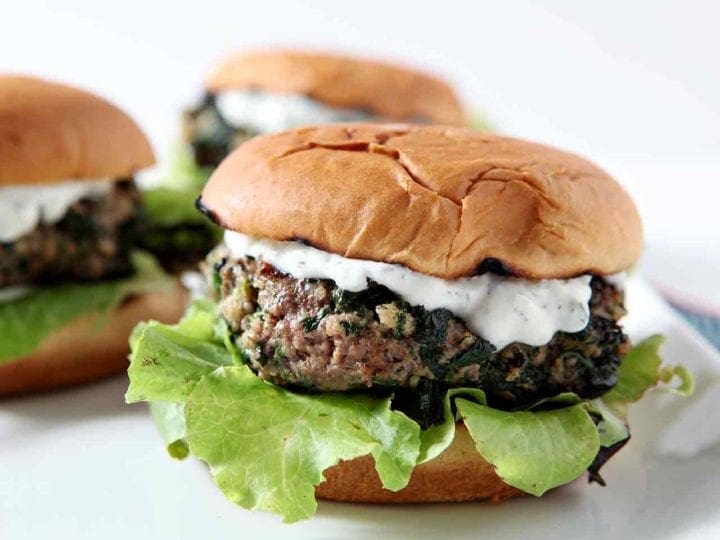 Three Spinach and Feta Burgers sit on a white platter, ready for consuming