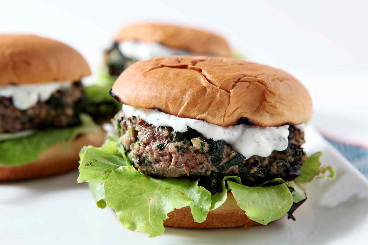 Three Spinach and Feta Burgers sit on a white platter, ready for consuming