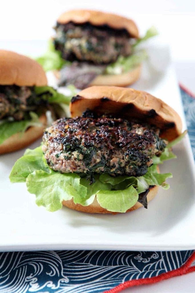 Cooked burgers, waiting for tzatziki, are on a platter