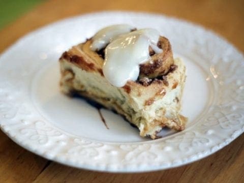 Cream Cheese icing drips off the top of a cinnamon roll