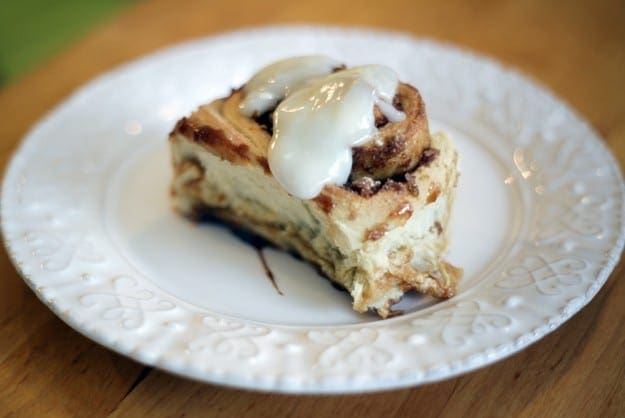 Cream Cheese icing drips off the top of a cinnamon roll