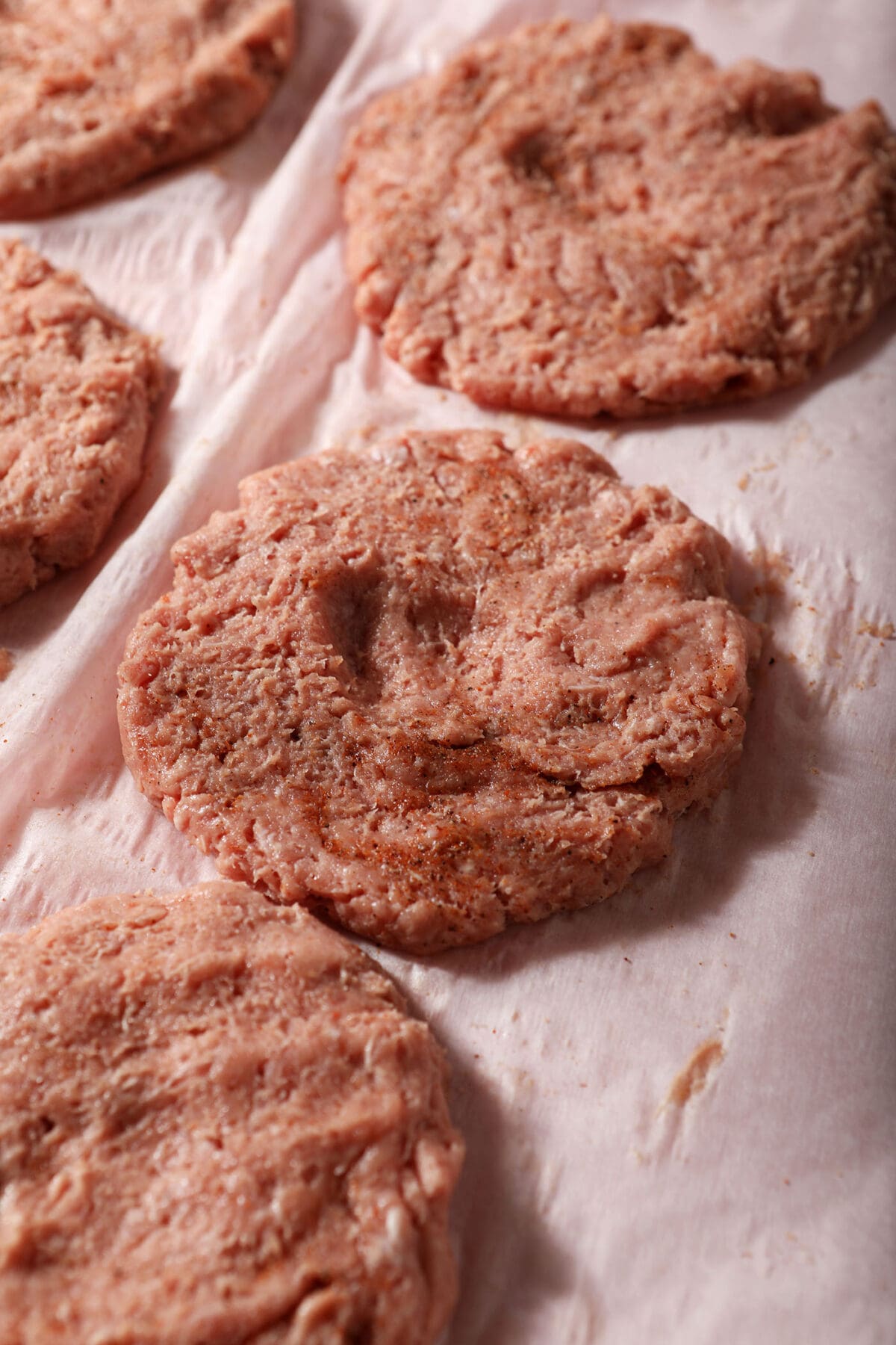 Ground turkey burger patties on parchment paper before grilling