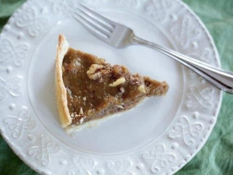 Overhead close up view showing slice of pie on white plate with a fork