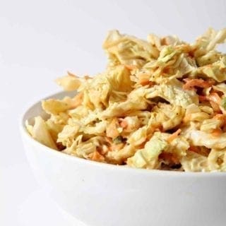 A bowl of No Mayo Honey Mustard Coleslaw sits on a white background.