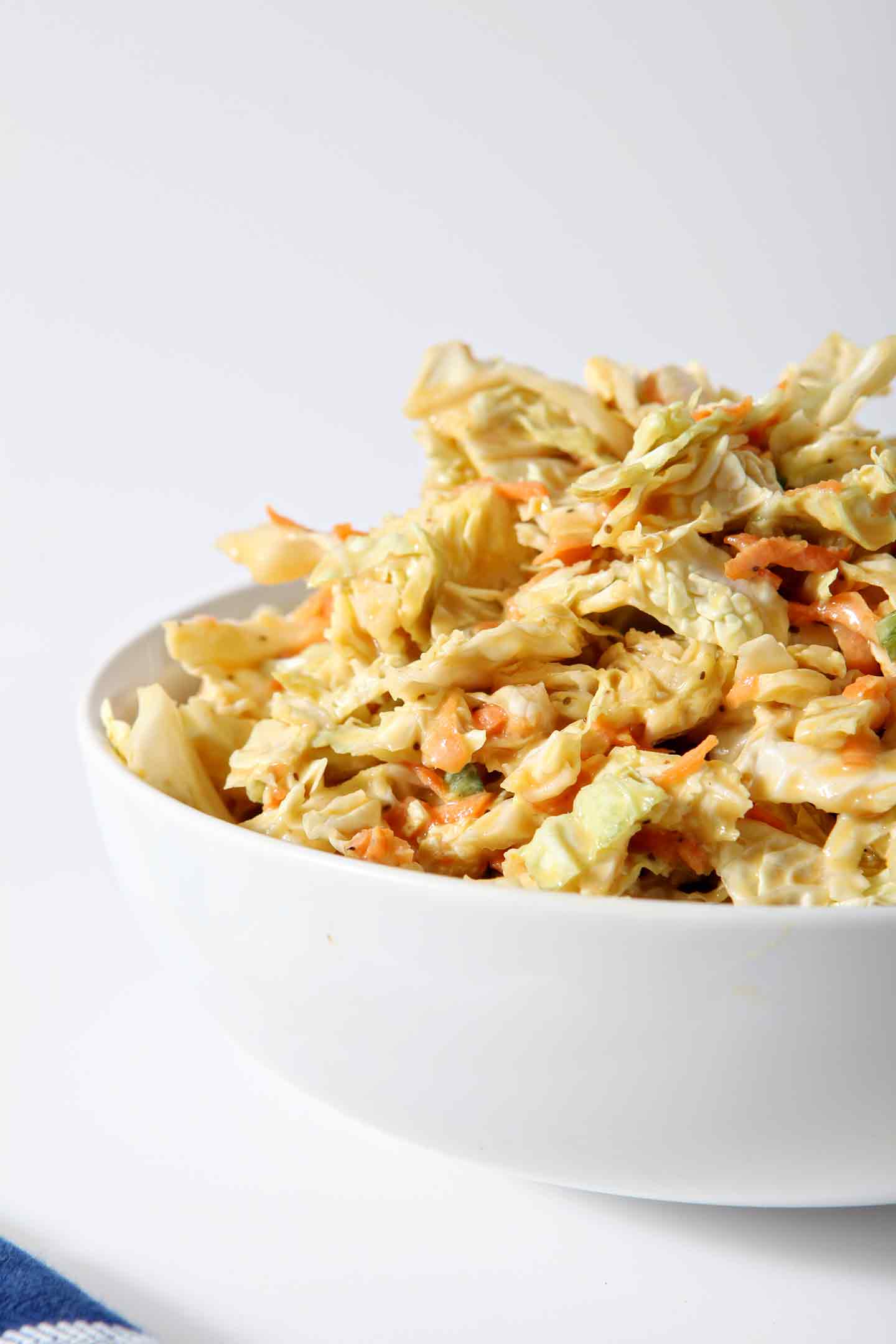 A bowl of No Mayo Honey Mustard Coleslaw sits on a white background.