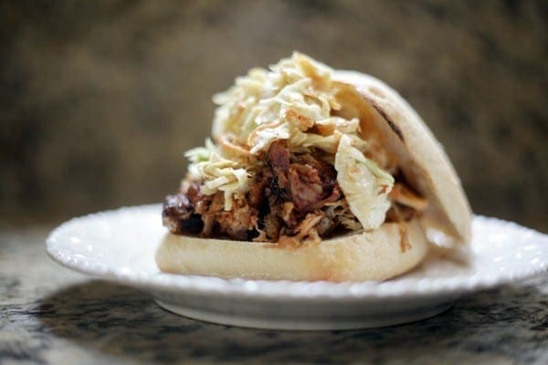 A BBQ Pulled Pork Sandwich with coleslaw on a plate on granite