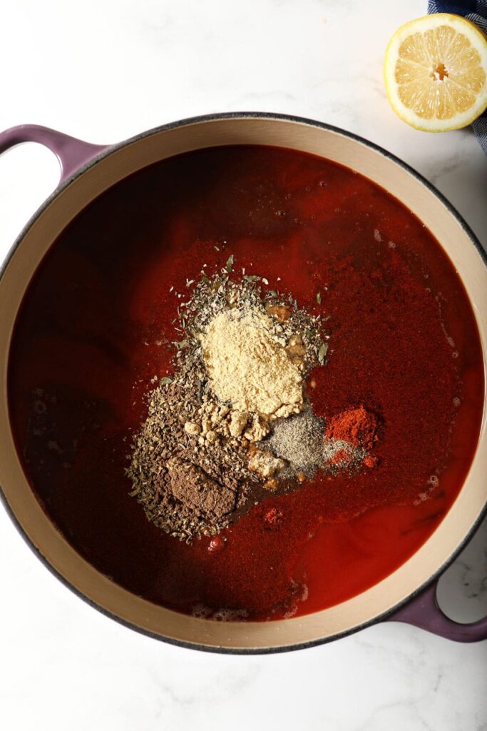 Spices on top of ingredients in a large Dutch oven from above