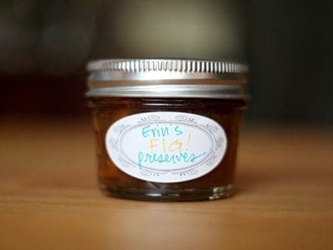 A small mason jar, labeled Erin's Fig Preserves, sits on a wooden table