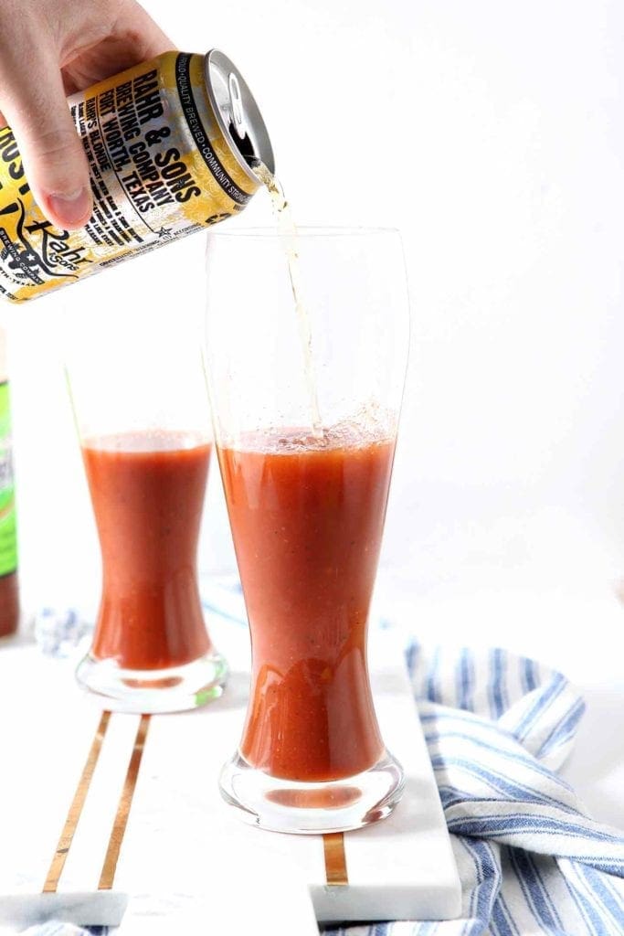 Beer is poured into a Spicy Bloody Beer Cocktail before drinking.