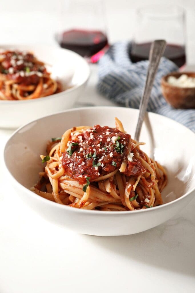 Close up of a white bowl holding spaghetti covered in marinara sauce