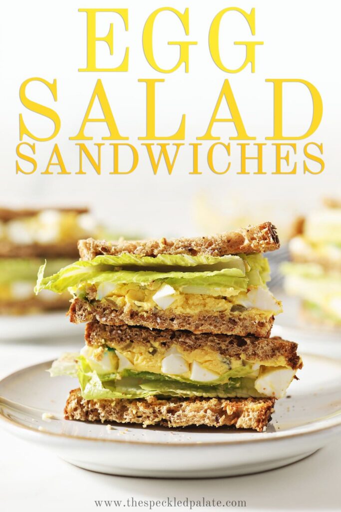 A halved sandwich stacked on a white plate with the text egg salad sandwiches