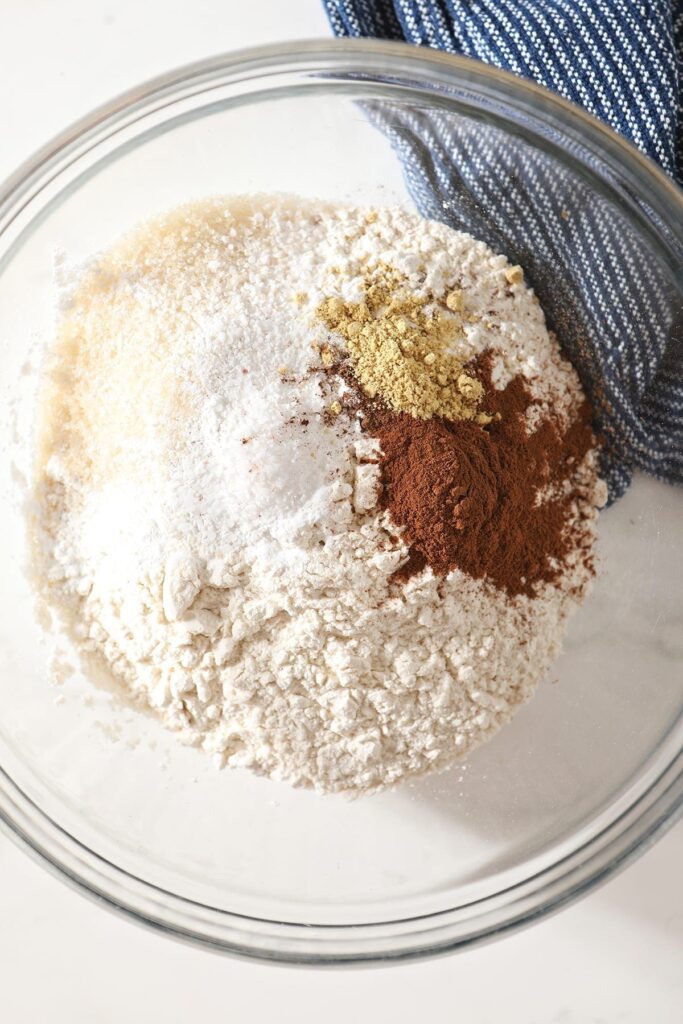 Dry ingredients and spices in a glass bowl on top of a marble counter