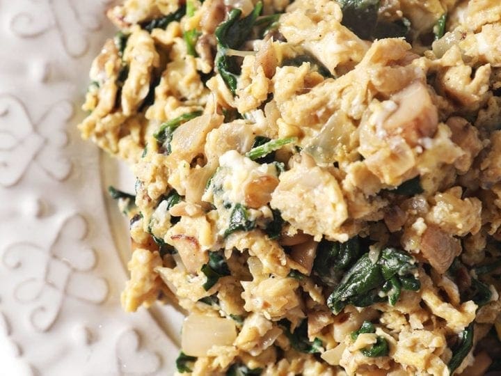 Close up of a serving of Scrambled Eggs with Spinach, mushrooms and onions on a white plate