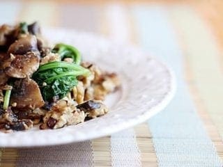 Scrambled eggs with mushrooms, spinach and more on a decorative white plate on a placemat