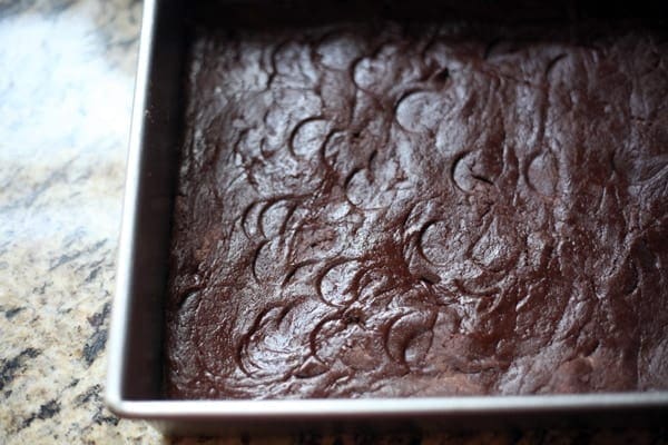 A brownie crust pressed into a baking pan