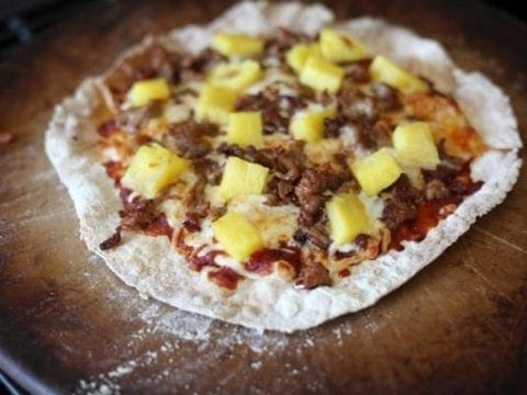 A close up of pork and pineapple pizza on pizza stone