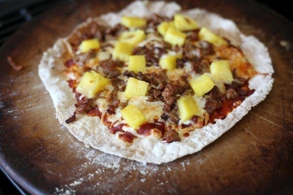 A close up of pork and pineapple pizza on pizza stone 