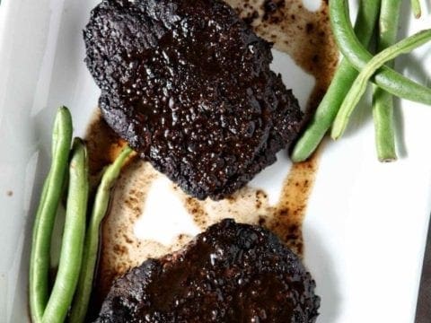 baked steak on a white plate with green beans