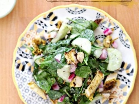 Chicken Schwarma Salad sits on a yellow, grey and black plate on a light wooden table
