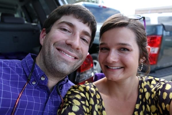 A man and woman wearing purple and gold apparel smile for the camera