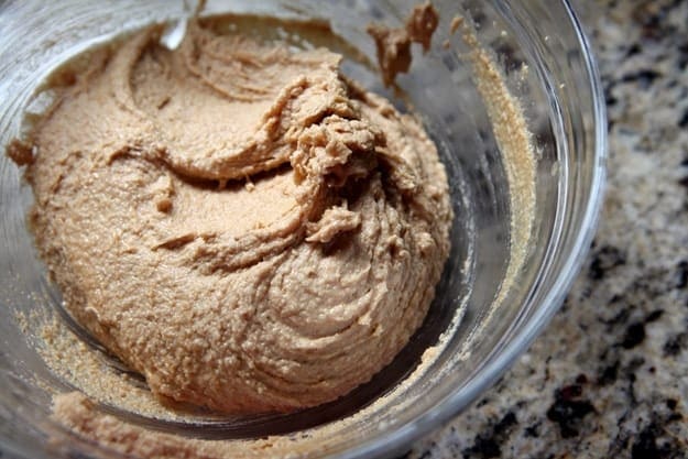 A glass bowl holds peanut butter cookie batter