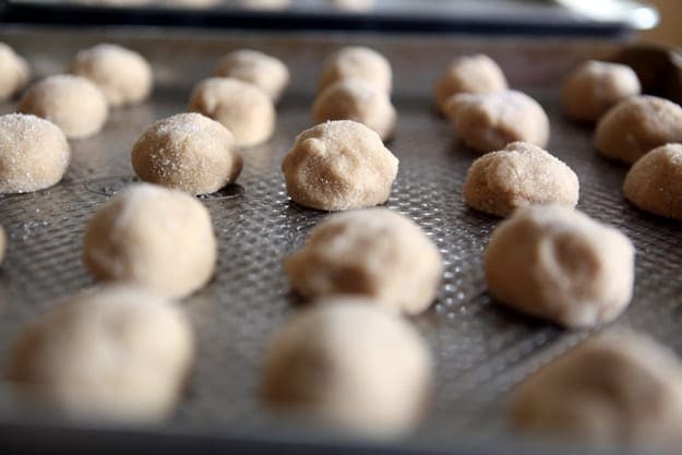 Peanut butter cookie balls on a metal baking sheet before baking