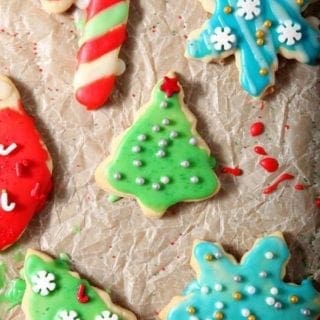 Decorated All-Butter Tea Cake Cookies are laid out on parchment paper to dry after icing and decorating