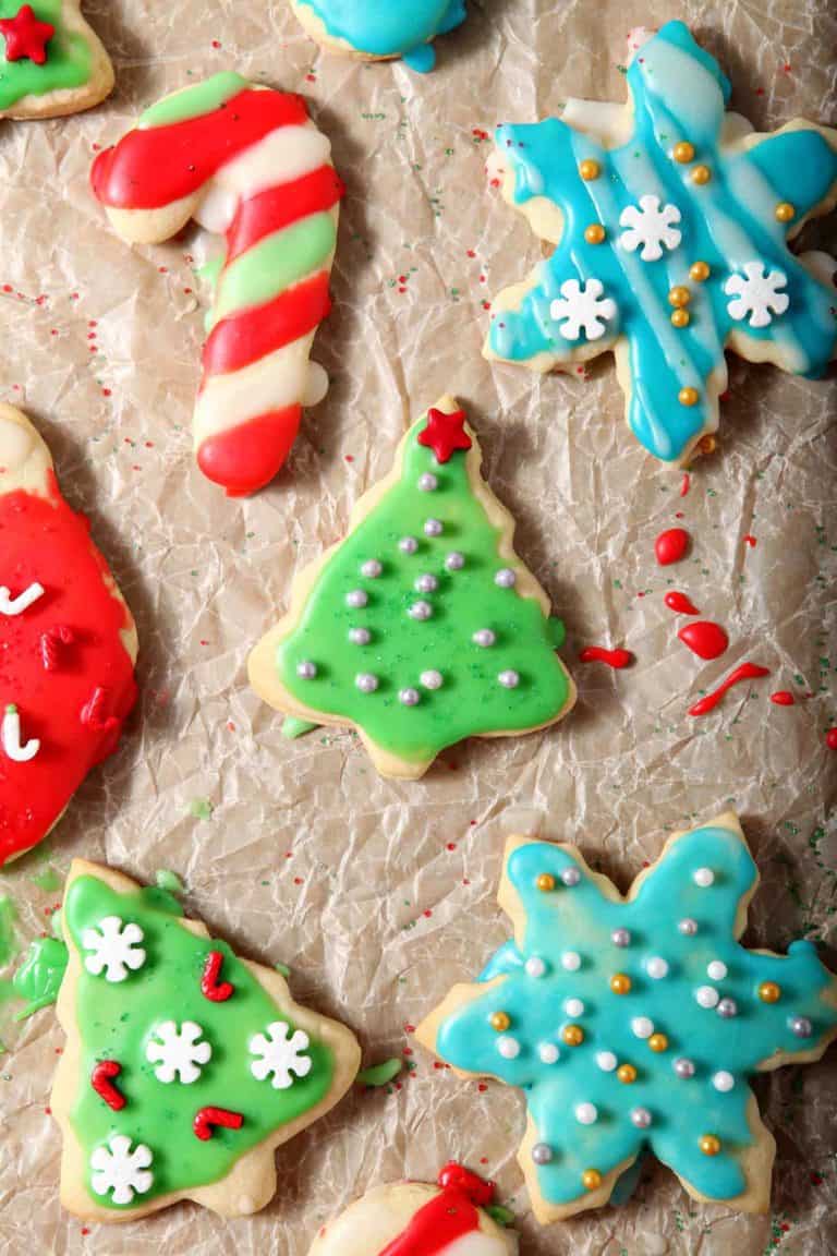 Decorated All-Butter Tea Cake Cookies are laid out on parchment paper to dry after icing and decorating