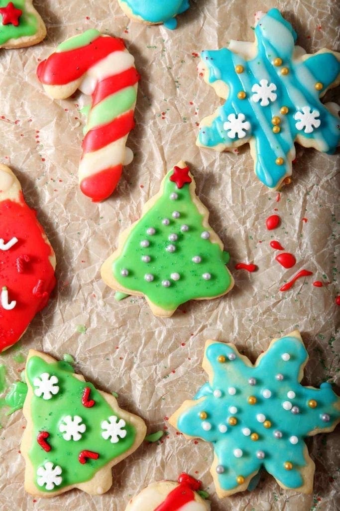 Decorated All-Butter Tea Cake Cookies are laid out on parchment paper to dry after icing and decorating