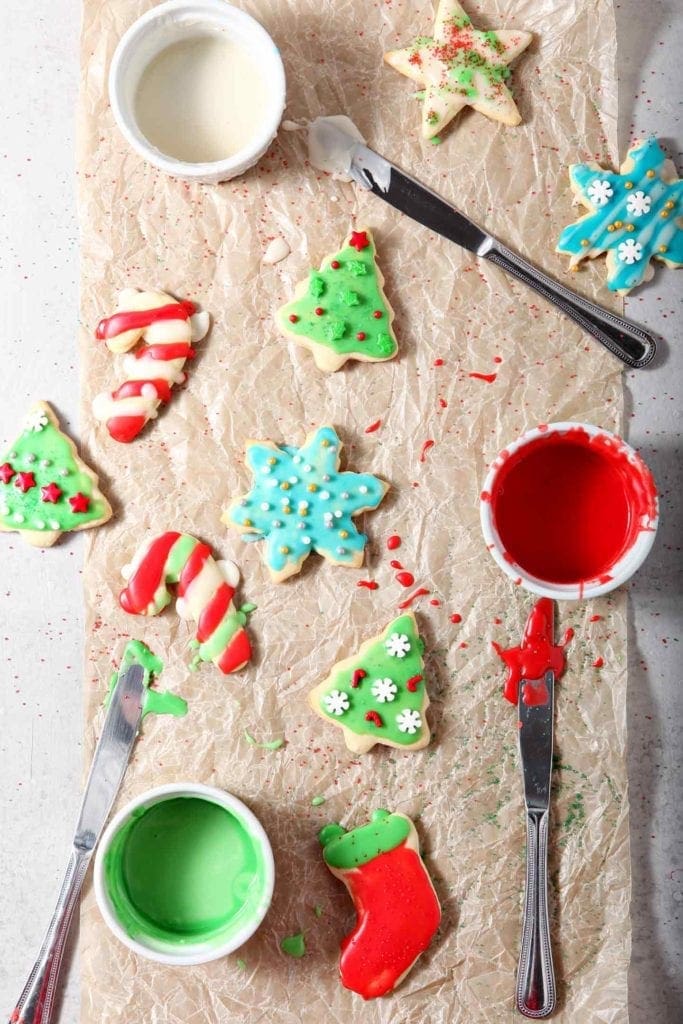 Overhead image of just-iced and decorated All-Butter Tea Cake Cookies drying on a piece of parchment paper, surrounded by decorating supplies