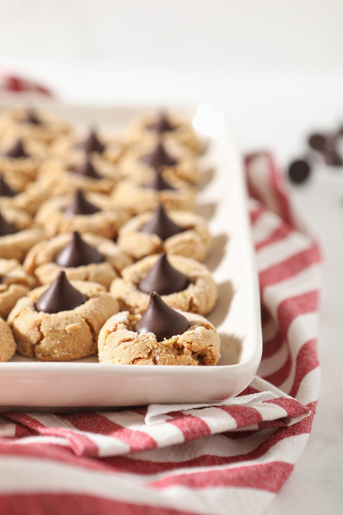 A tray of Dark Chocolate Peanut Butter Blossom Cookies on top of a red and white striped towel