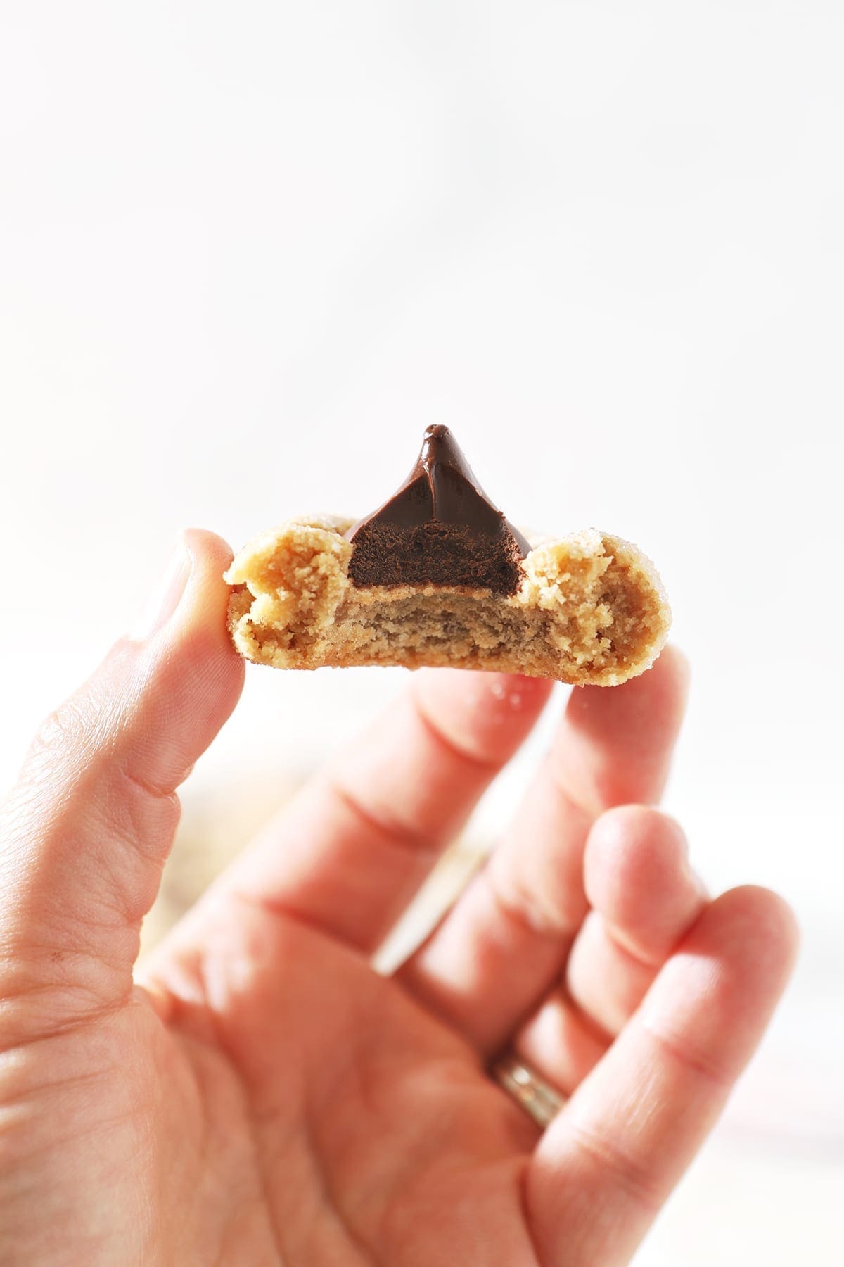 A hand holds a bitten-into a hershey kiss cookie