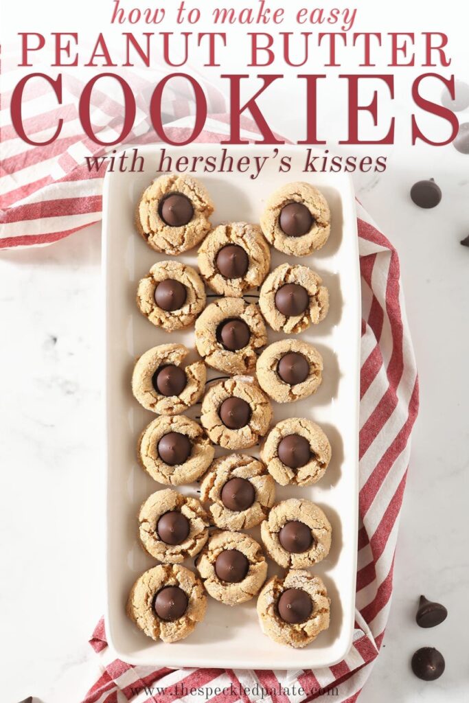 A tray of Dark Chocolate Peanut Blossom Cookies from above sitting on top of a red and white striped towel on a marble countertop with the text 'how to make easy peanut butter cookies with hershey's kisses'