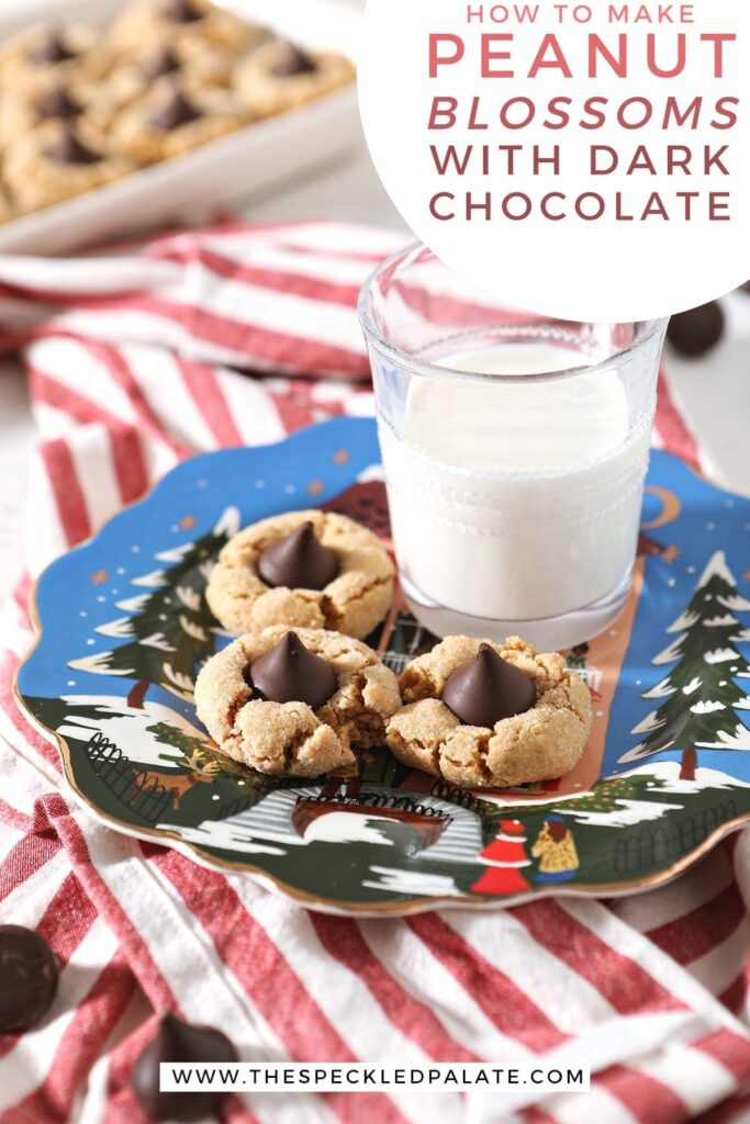 Three Dark Chocolate Peanut Blossoms sit on a blue painted plate next to a glass of milk on top of a red and white striped towel with the text 'how to make peanut butter blossoms with dark chocolate'