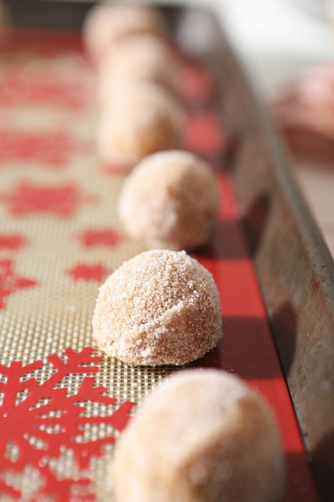 Peanut Blossom cookie dough on a snowflake-lined baking sheet before baking