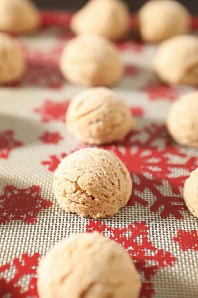 A festive red and white silat holds baked peanut blossom cookies before the Kisses are added