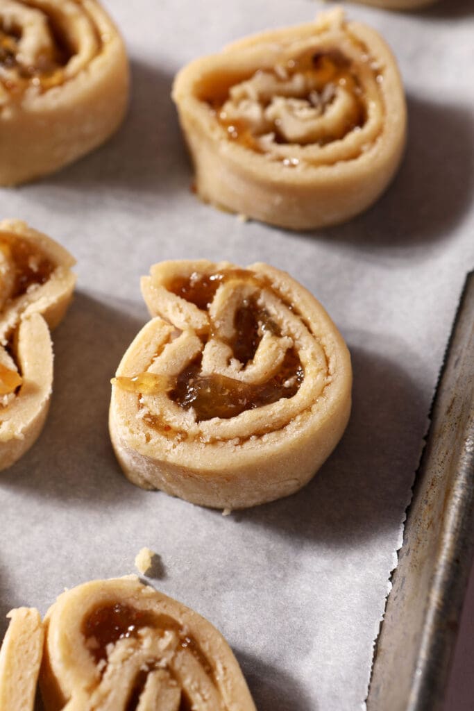 sliced pinwheel cookies on a lined sheet pan