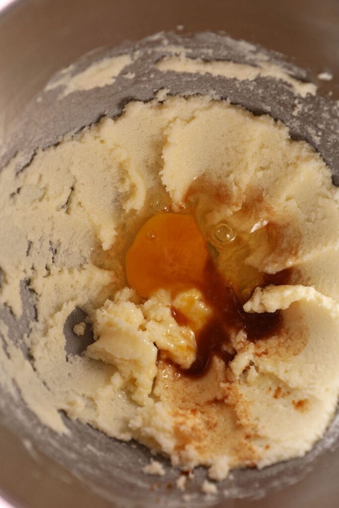 egg and vanilla extract added to creamed butter and sugar in a metal bowl