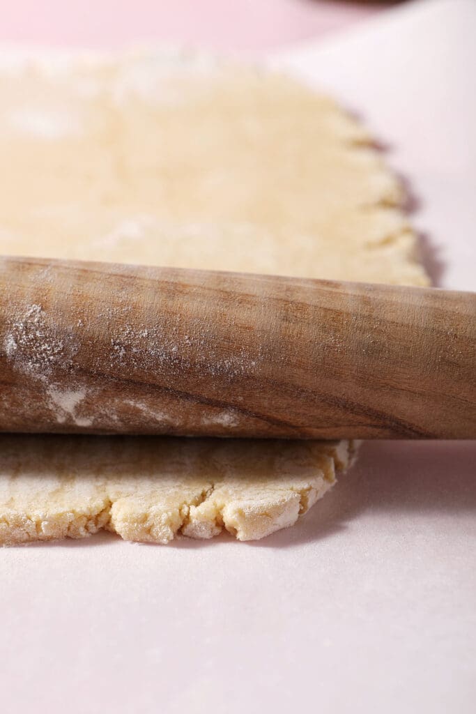 a wooden rolling pin rolls out a cookie dough