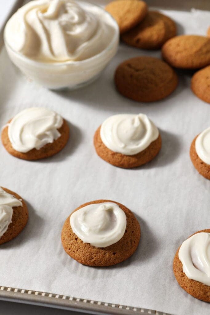 Baked cookies frosted with cream cheese frosting on a sheet pan