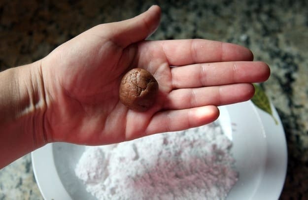 A ball of chocolate crinkle cookie dough in a hand