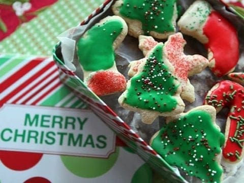Iced and sprinkled Christmas trees, stockings, snowflakes and candy cane cookies in a red, white and green Merry Christmas cookie tin