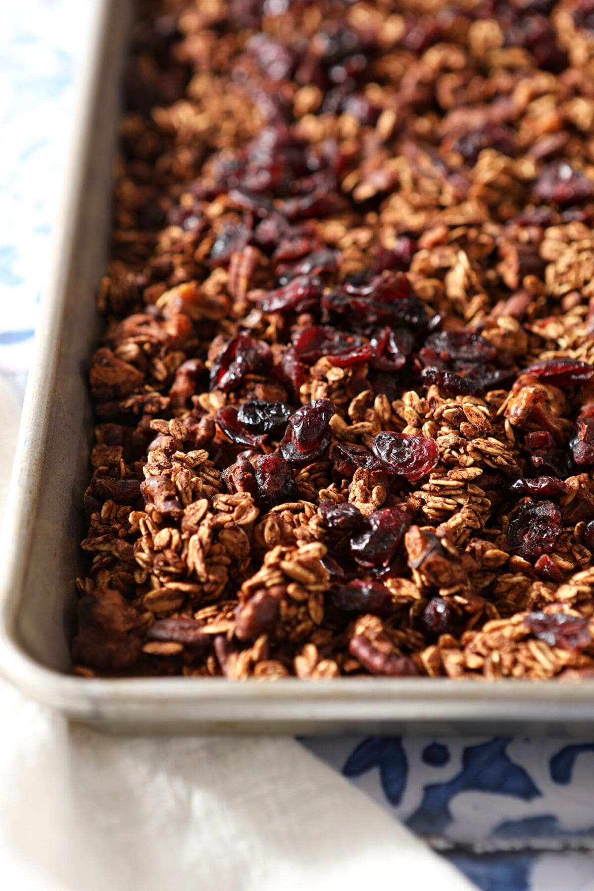 A baking sheet of granola with dried cranberries on a tiled surface