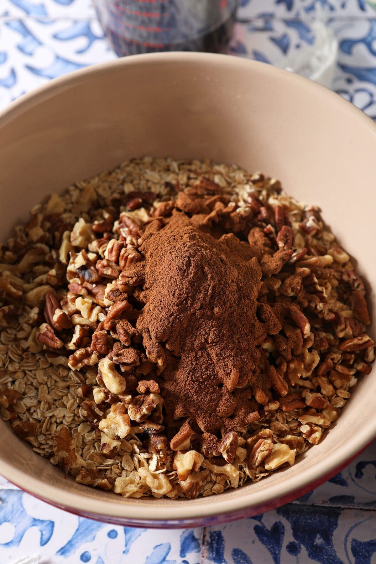 A large bowl with oats, nuts and cinnamon before tossing together