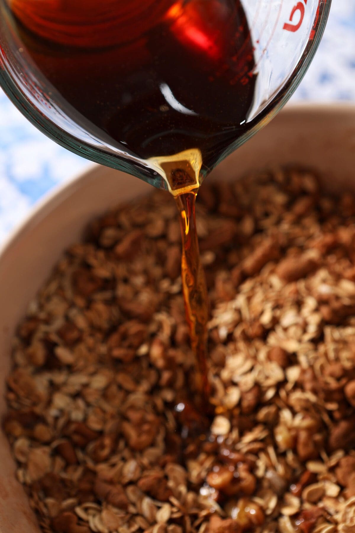 A maple-water mixture pours on top of granola ingredients before mixing