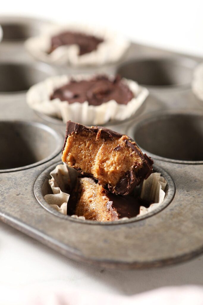 A halved peanut butter cup in a muffin tin