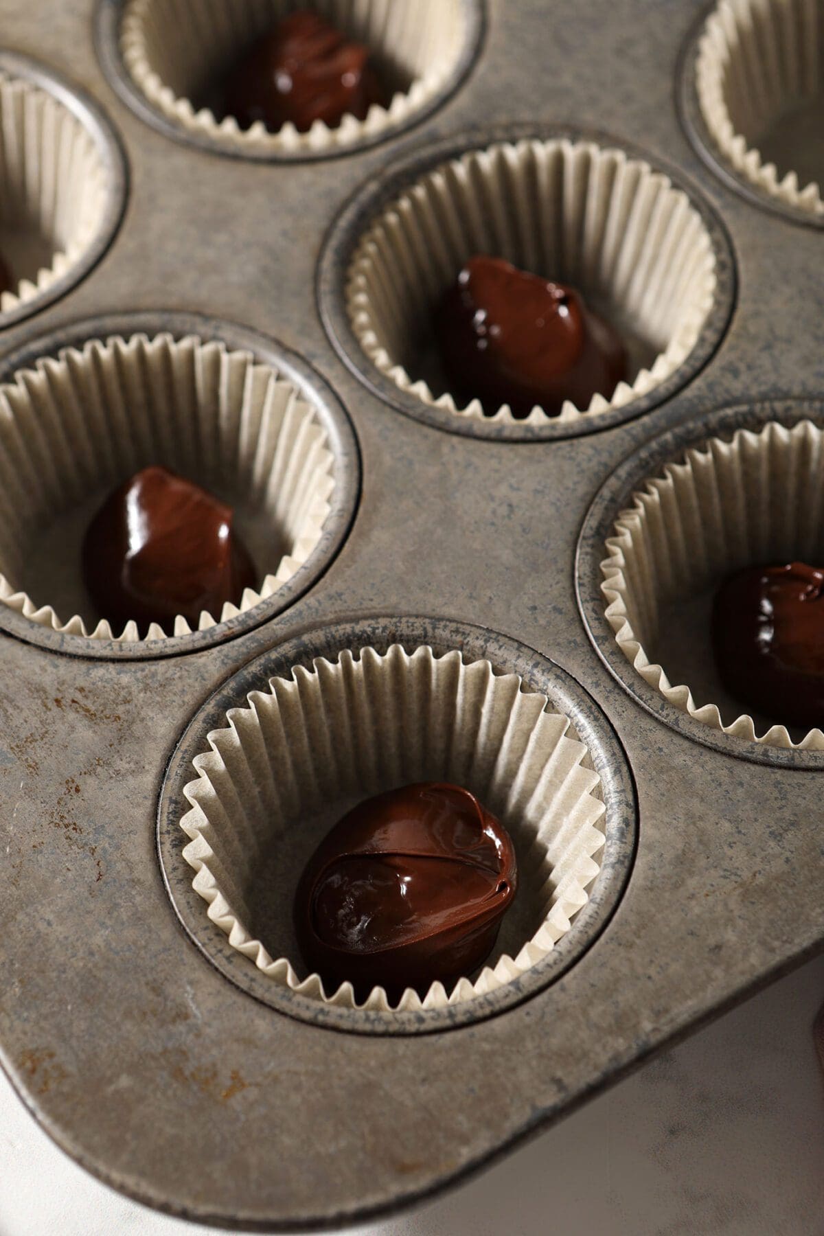 Dollops of chocolate in muffin liners in a muffin tin