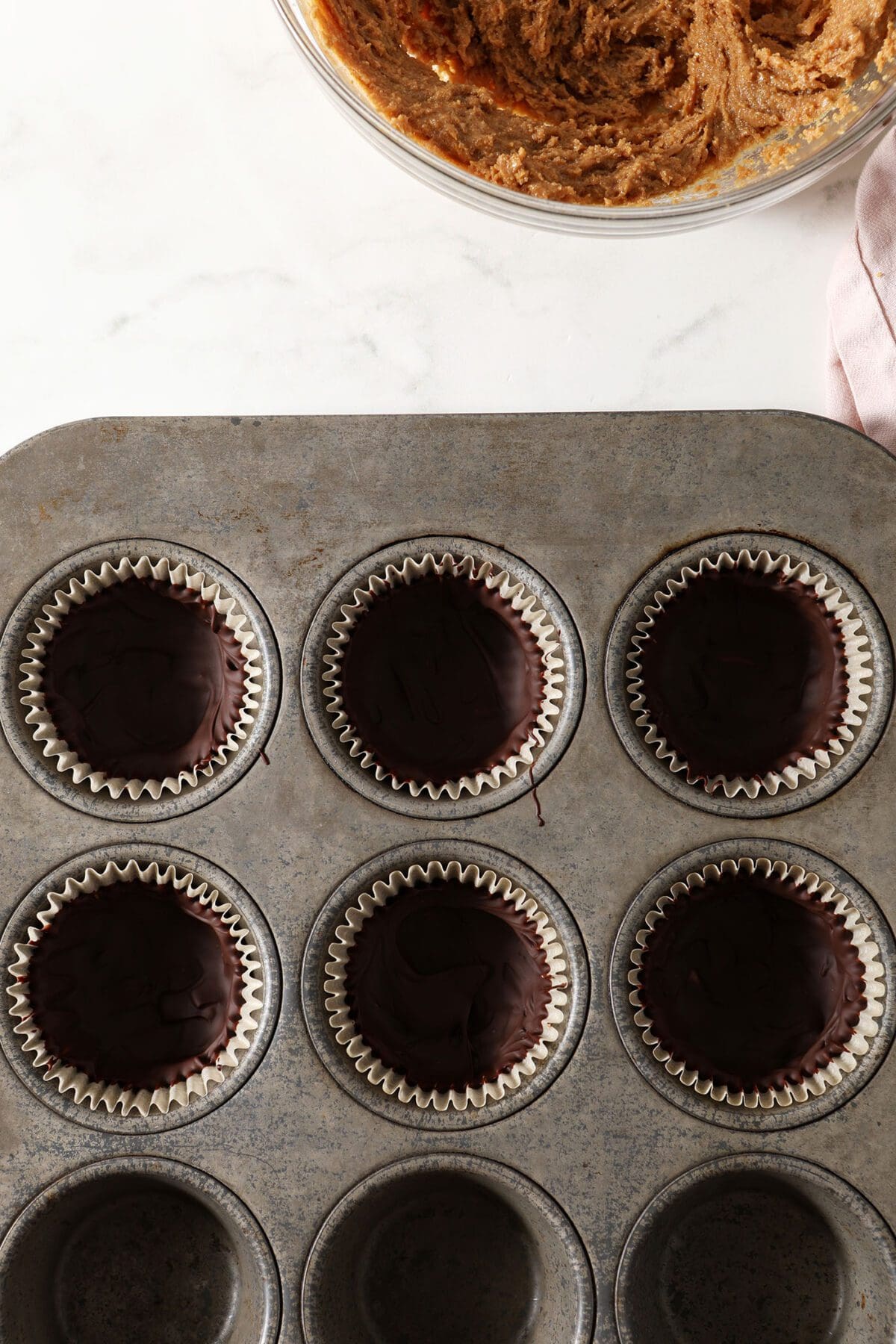 Cold chocolate-lined muffin liners in a muffin tin